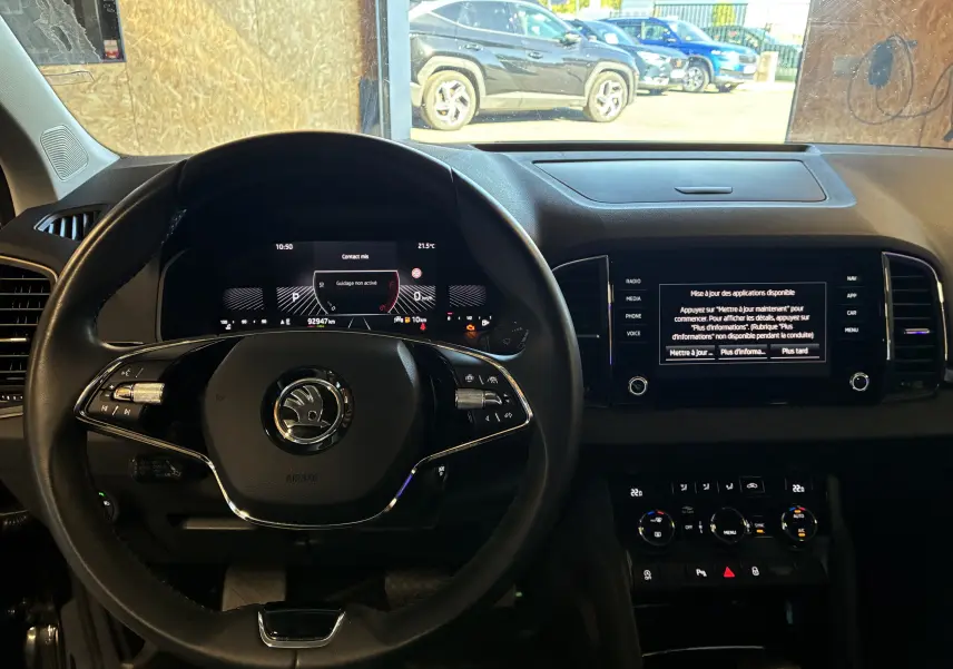 Vue intérieure centrée sur le volant multifonctions et le tableau de bord numérique du Skoda Karoq noir 2024.