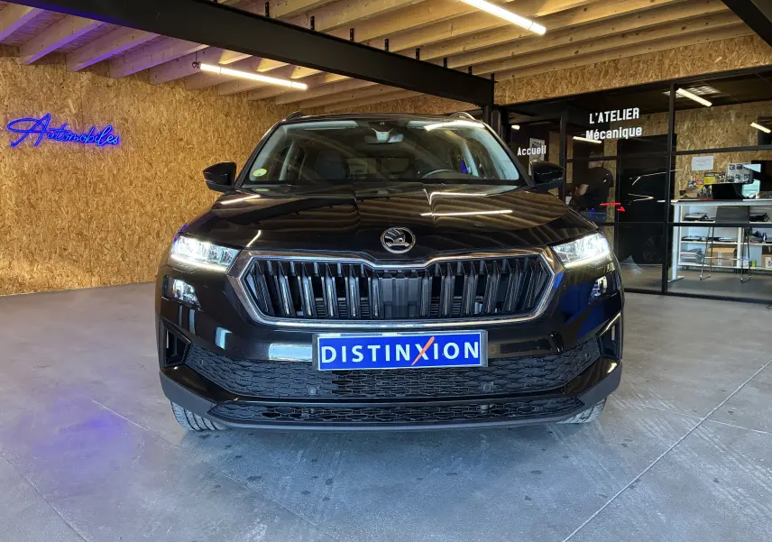 Vue frontale d'un Skoda Karoq noir 2024 avec calandre noire et contours chromés, phares allumés en intérieur.