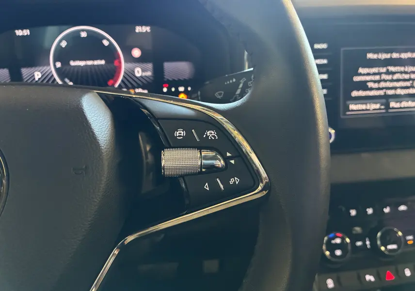 Gros plan sur le volant noir du Skoda Karoq 2024, avec commandes multifonctions chromées et tableau de bord digital en arrière-plan.