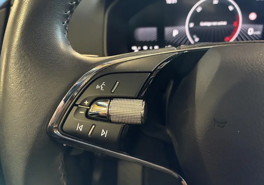 Gros plan sur la commande gauche du volant noir du Skoda Karoq 2024 avec molette chromée et boutons multifonctions.