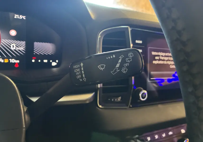 Gros plan sur la commande d'essuie-glace noire à gauche du volant dans l'habitacle du Skoda Karoq 2024.