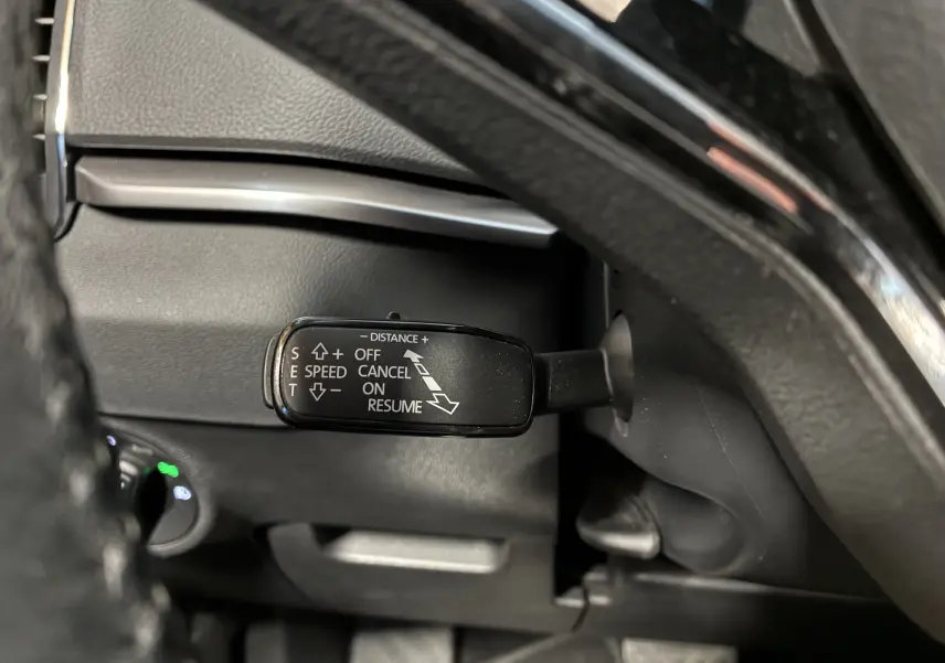 Gros plan sur la commande de régulateur de vitesse adaptatif noire dans l'habitacle du Skoda Karoq 2024.