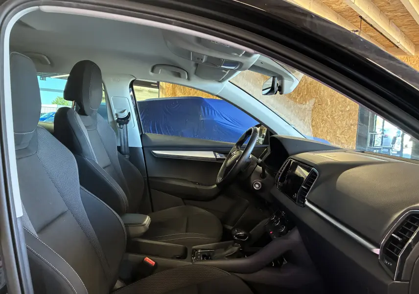 Intérieur noir de la Skoda Karoq 2024 vu côté conducteur, avec tableau de bord et sièges en tissu.