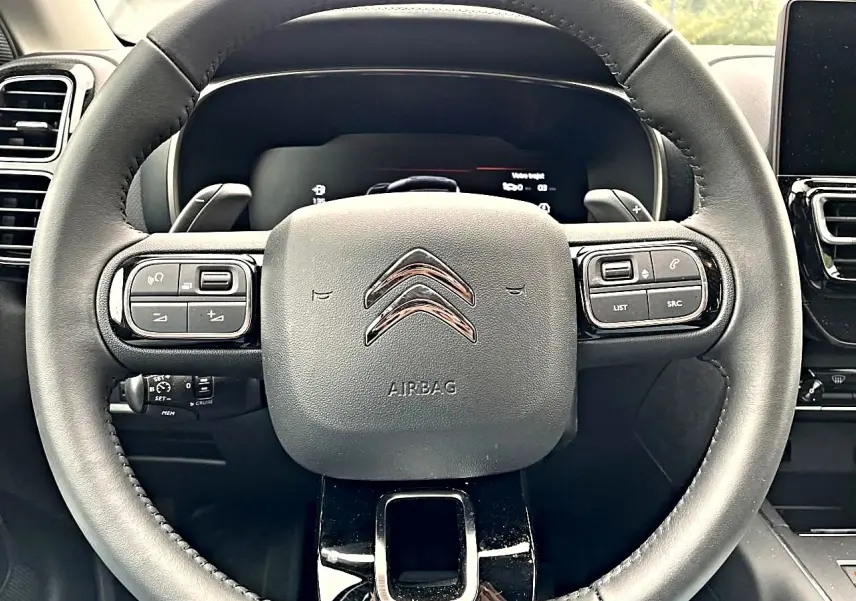 Vue rapprochée du volant noir multifonction du Citroën C5 Aircross avec commandes intégrées et logo chromé au centre.