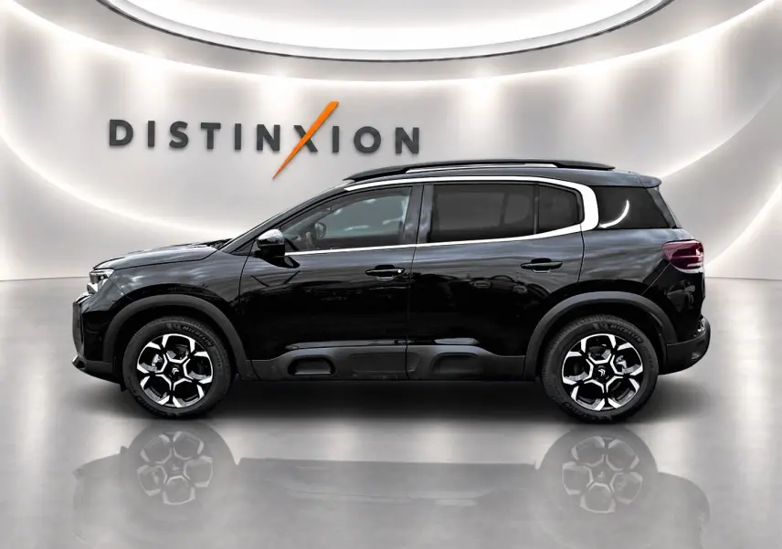 Profil droit du SUV Citroën C5 Aircross noir 2025 avec jantes alliage et barres de toit visibles en showroom.