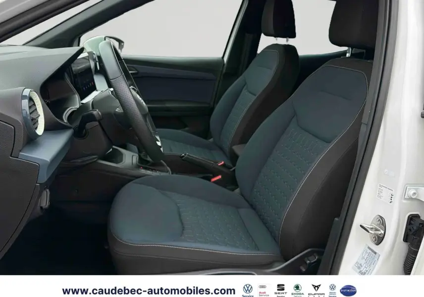 Vue intérieure côté conducteur du SEAT Arona blanc 2026, montrant les sièges avant en tissu gris et volant cuir multifonction.