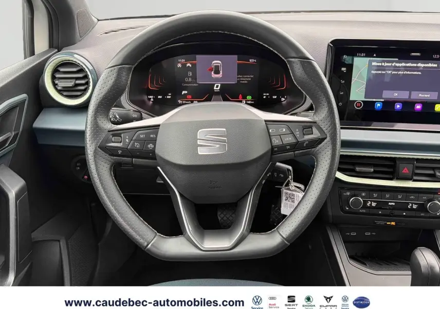 Vue intérieure centrée sur le volant cuir noir du SEAT Arona 2026 avec tableau de bord numérique et écran tactile.