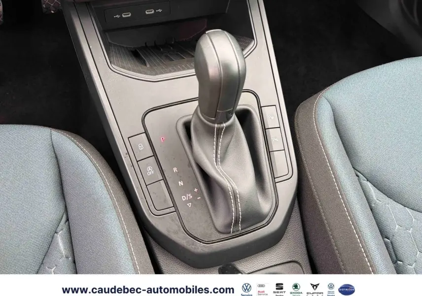 Gros plan sur la console centrale du SEAT Arona 2026, montrant le levier de vitesses DSG noir et les sièges tissu gris.