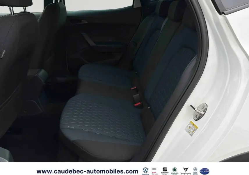 Vue intérieure côté arrière droit du SEAT Arona blanc, montrant les sièges arrière en tissu bleu et noir.