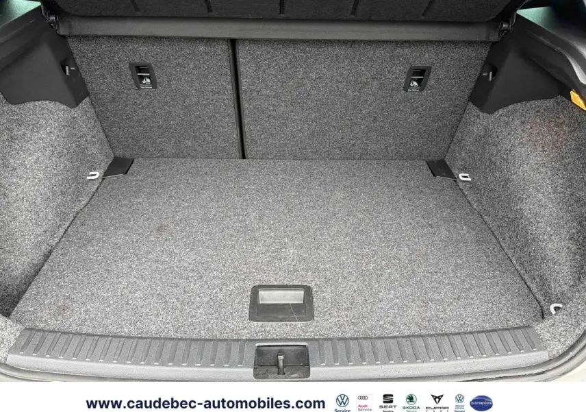 Coffre spacieux et propre du SEAT Arona blanc, vue intérieure avec revêtement gris et éclairage latéral.