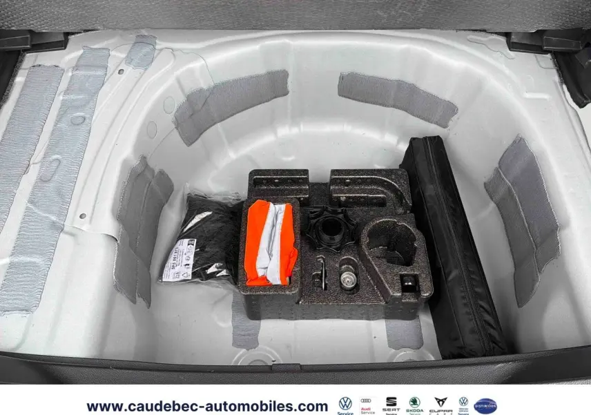 Coffre ouvert du SEAT Arona blanc montrant le rangement sous plancher avec kit de secours et outils.