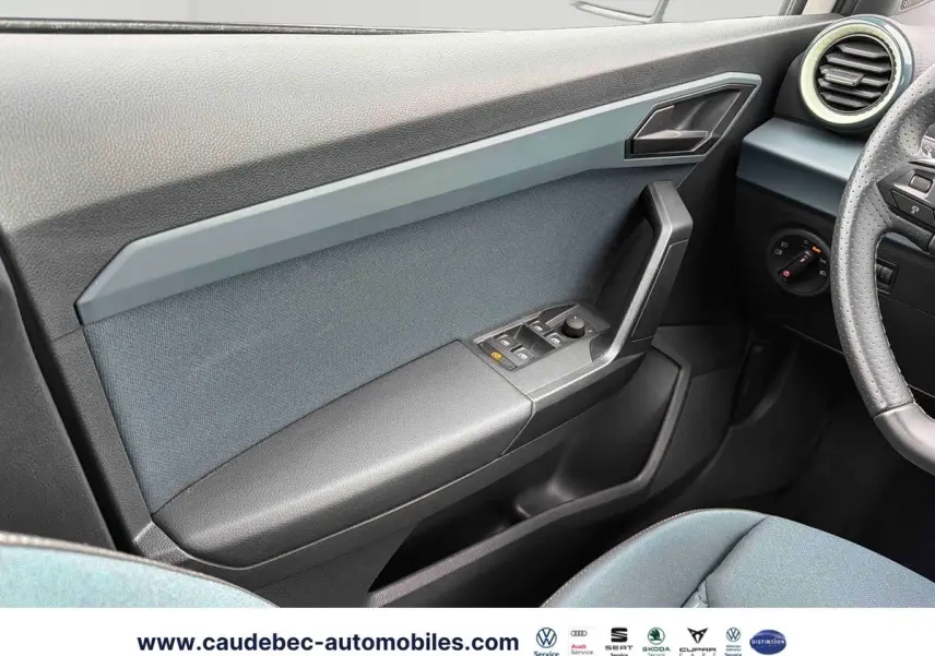 Vue intérieure côté conducteur du panneau de porte gris et noir du SEAT Arona 2026 avec commandes électriques des vitres.