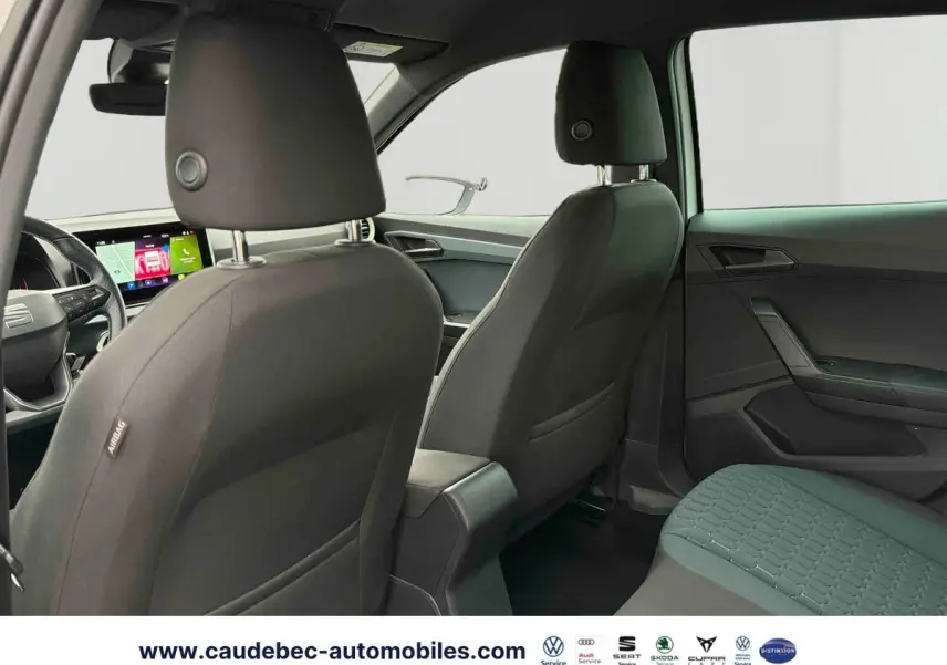 Intérieur arrière du SEAT Arona blanc, vue depuis la porte arrière gauche avec sièges noirs et tableau de bord digital visible.