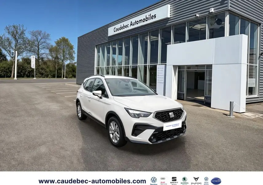 SEAT Arona blanc en 3/4 avant droit devant un bâtiment de concession avec jantes alliage 16 pouces design.