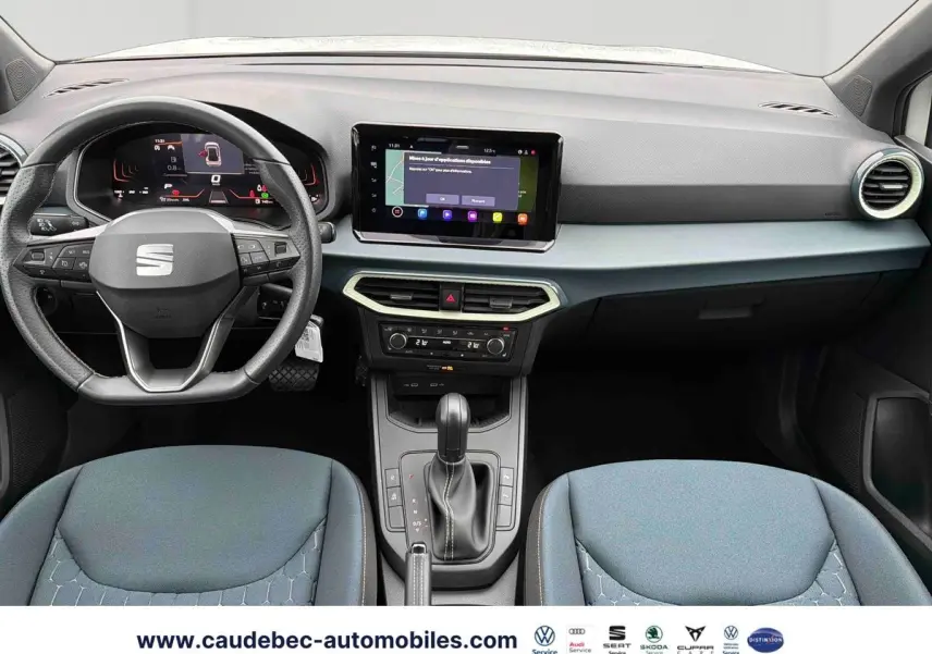 Vue intérieure avant du tableau de bord et volant noir de la SEAT Arona avec écran tactile central allumé.