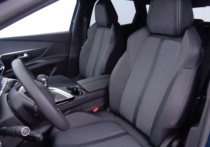 Vue intérieure côté conducteur du Peugeot 3008 2023, sièges en tissu gris et cuir noir avec surpiqûres bleues.