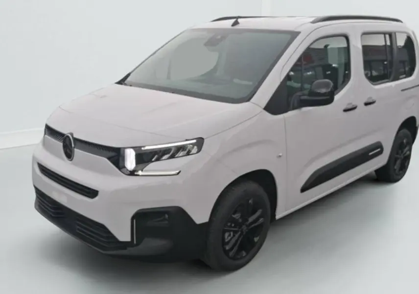 Citroën Berlingo blanc en 3/4 avant droit avec jantes noires et barres de toit visibles sur fond clair.