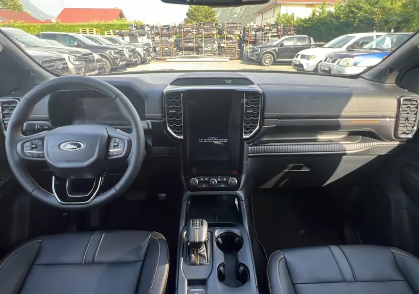 Intérieur du Ford Ranger Wildtrak 2025 vu de face, tableau de bord noir avec coutures orange et écran central vertical.
