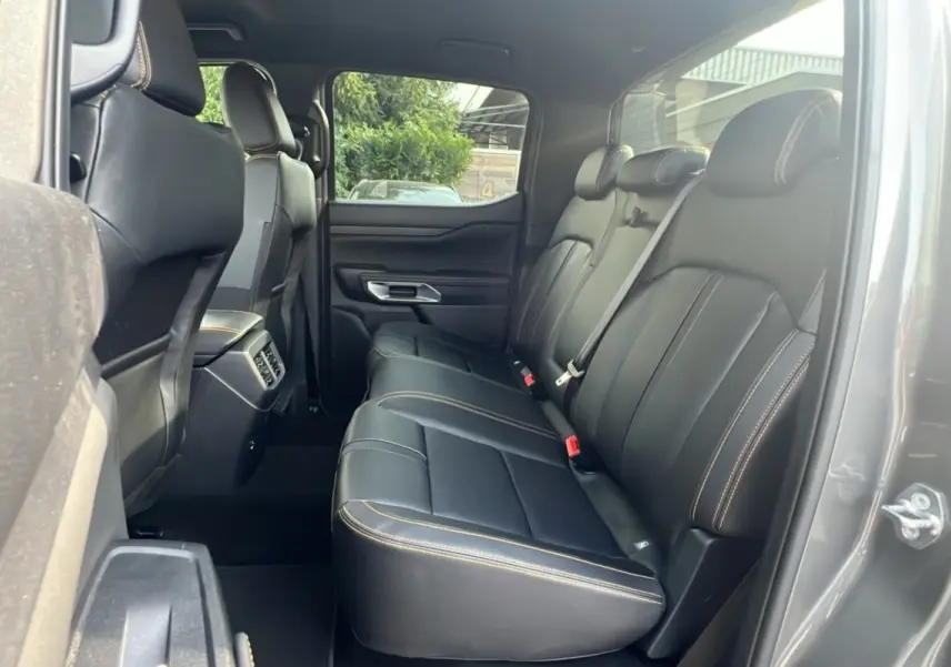 Vue intérieure arrière droite du Ford Ranger 2025 gris carbone, montrant les sièges en cuir noir avec surpiqûres contrastées.