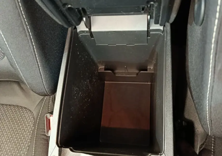 Vue plongeante sur le rangement central ouvert entre les sièges noirs du Renault Kadjar Business gris foncé 2022.