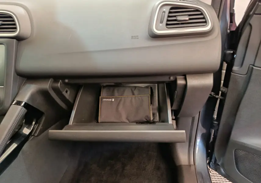Gros plan sur la boîte à gants ouverte côté passager du Renault Kadjar gris foncé avec pochette Renault visible.