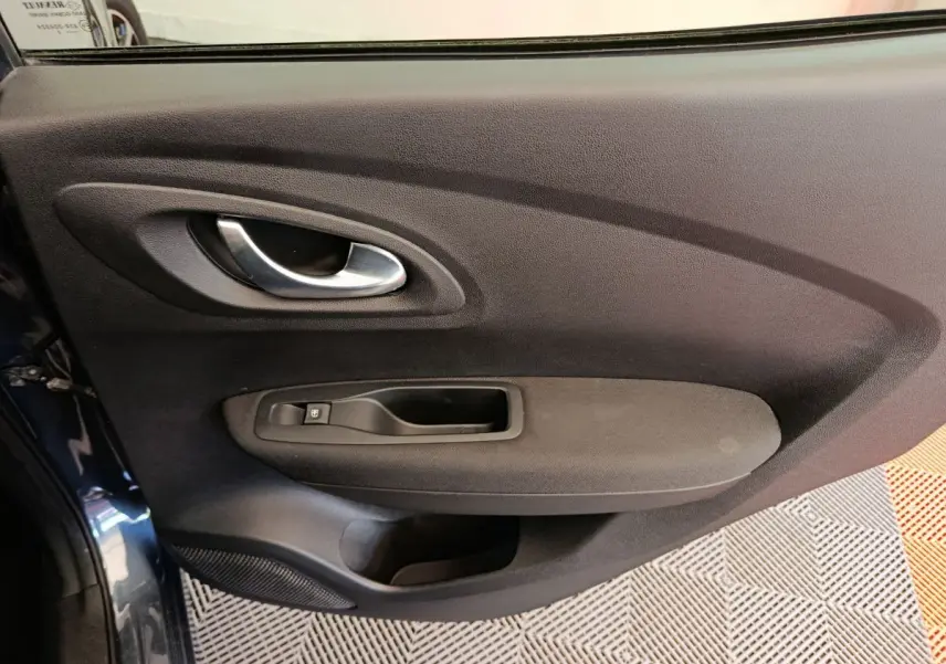 Gros plan sur la porte intérieure côté gauche du Renault Kadjar Business gris foncé, avec poignée argentée et commande de vitre.