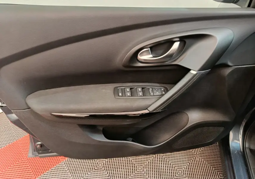 Gros plan sur la porte côté conducteur du Renault Kadjar gris foncé, avec commandes électriques et poignée argentée.