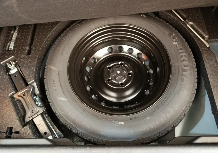Gros plan sur la roue de secours noire et le cric dans le coffre d’un Renault Kadjar gris foncé 2022.
