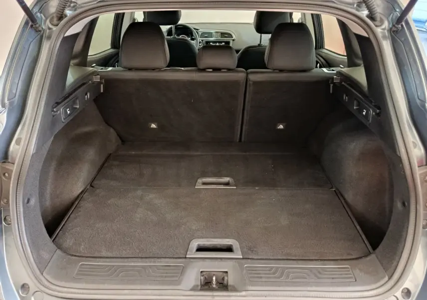 Vue depuis l'arrière du coffre spacieux du Renault Kadjar Business gris foncé avec banquette rabattue et intérieur noir.