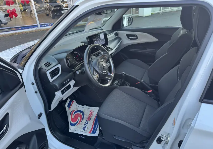 Intérieur de la Suzuki Swift 1.2 Privilège Hybrid 2025 vue côté conducteur, sièges noirs et tableau de bord moderne.