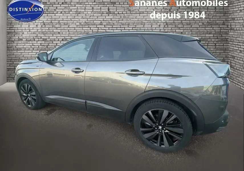 Vue latérale gauche d’un Peugeot 3008 gris foncé avec jantes noires et toit noir brillant, sur fond de mur en briques.