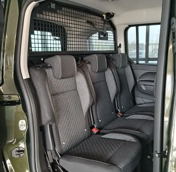 Vue intérieure côté droit des trois sièges arrière noirs du Peugeot Rifter 2025 en Srikka Green avec séparation grillagée.