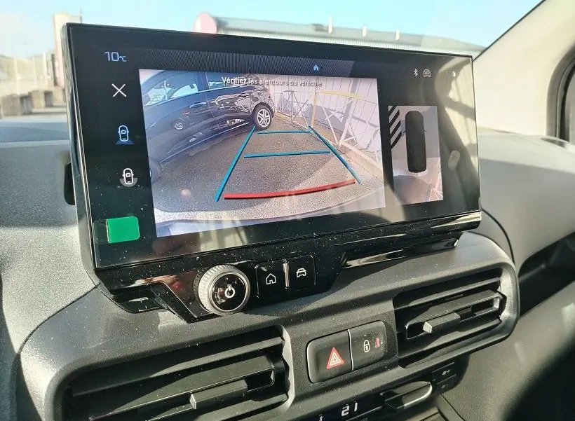 Vue intérieure du tableau de bord du Peugeot Rifter 2025, écran tactile affichant la caméra de recul avec lignes de guidage.