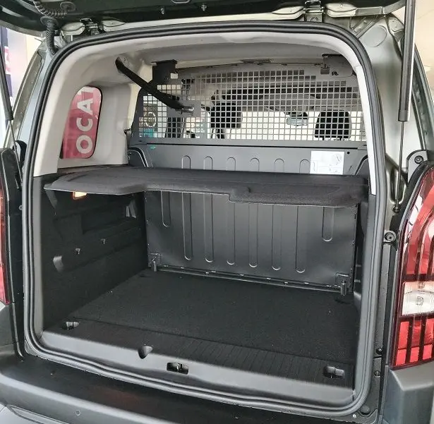 Vue arrière ouverte du Peugeot Rifter 2025 vert Srikka, montrant le coffre spacieux avec séparation grillagée.