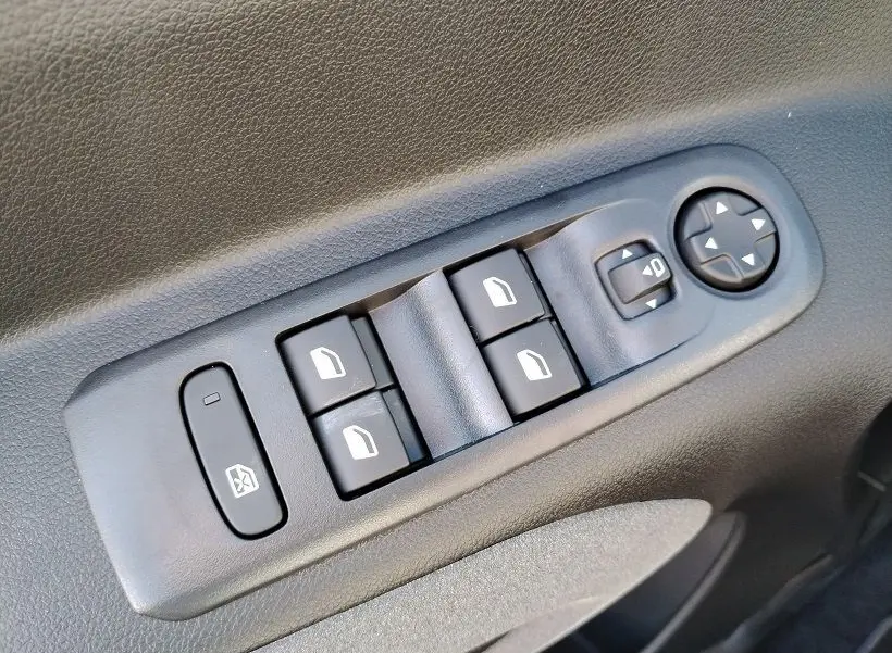 Commande des vitres électriques et réglage des rétroviseurs sur la porte intérieure noire du Peugeot Rifter 2025.