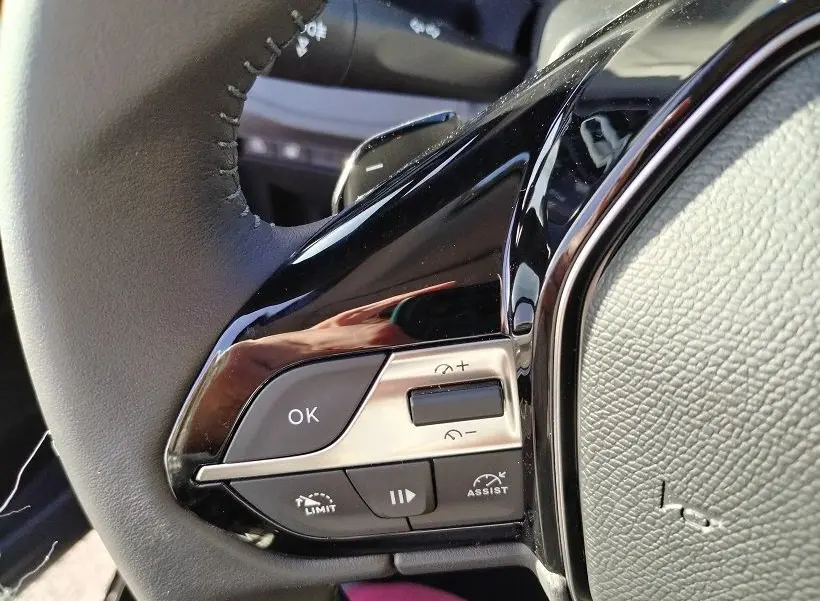 Gros plan sur les commandes gauche du volant noir du Peugeot Rifter 2025, avec boutons de régulateur et finition brillante.