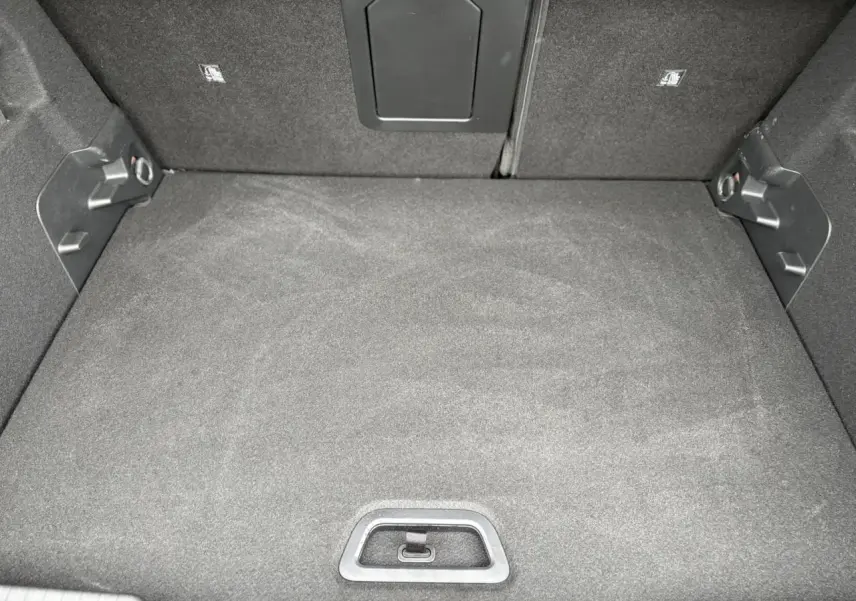 Vue plongeante sur le coffre spacieux et tapissé de tissu noir du Citroën C4 Hybrid 2025.