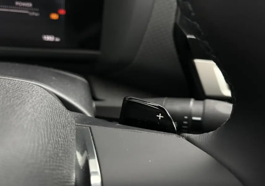 Gros plan sur la palette de changement de rapports "+" côté droit du volant cuir d'une Citroën C4 Hybrid 2025.