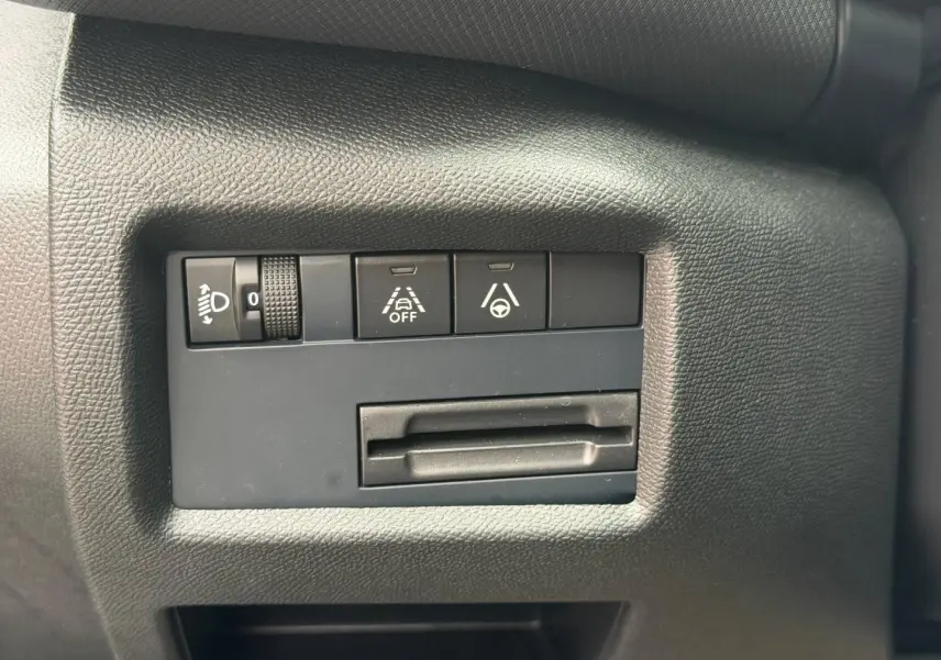 Gros plan sur les commandes de réglage des phares et d'aide à la conduite du tableau de bord du Citroën C5 Aircross noir.