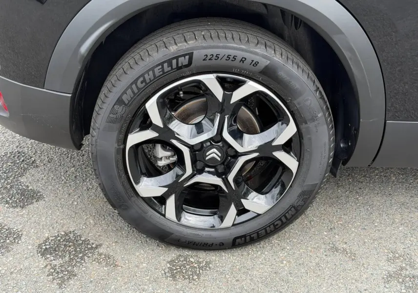 Gros plan sur la roue arrière droite noire Perla Nera du Citroën C5 Aircross avec jante alu bicolore et logo Citroën central.