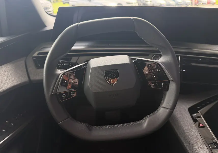 Vue rapprochée du volant cuir noir du Peugeot 1007 Hybrid 145 avec commandes intégrées et logo lion central.