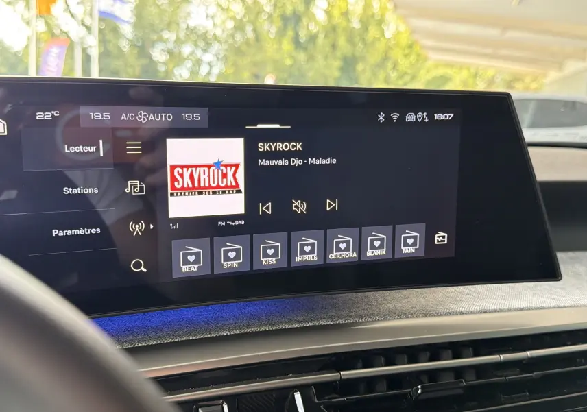 Écran tactile central affichant la radio Skyrock dans l’habitacle gris artense du Peugeot 1007 hybride, vue de face.