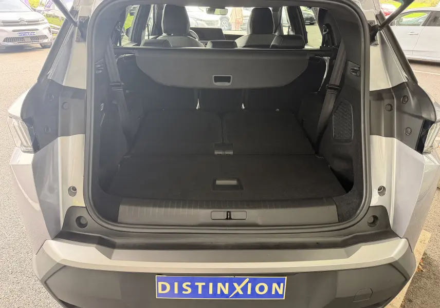 Coffre ouvert vu de l'arrière d'un Peugeot 1007 gris artense, banquette arrière rabattue et cache-bagages en place.