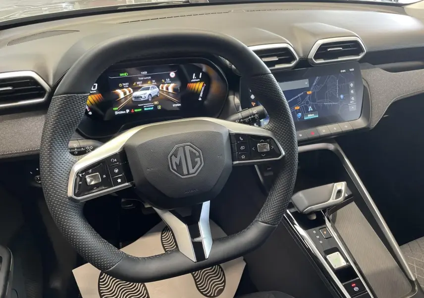 Vue intérieure centrée sur le volant cuir et le tableau de bord numérique du MG ZS 1.5 Hybrid+ gris clair, avec écran tactile.