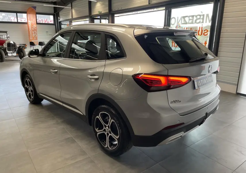 Vue 3/4 arrière droite d’un MG ZS gris clair 2026 avec feux LED allumés et jantes alliage 17 pouces en showroom.