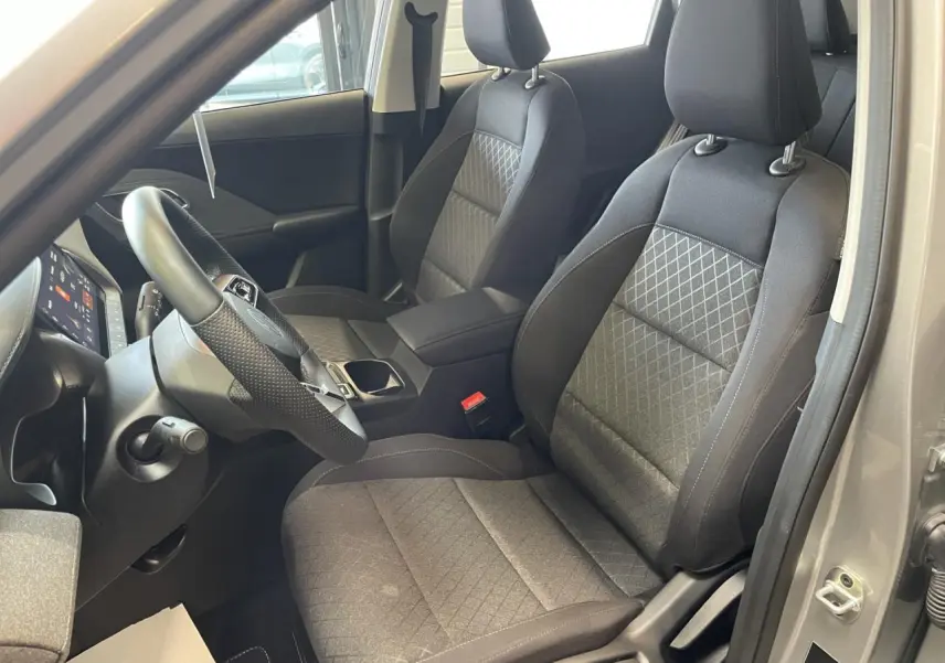 Vue intérieure côté conducteur du MG ZS 1.5 Hybrid+ 2026, sièges tissu noir avec motifs losanges et volant cuir.