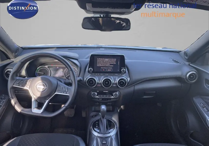 Vue frontale de l'habitacle du Nissan Juke gris, avec tableau de bord numérique et écran tactile central.
