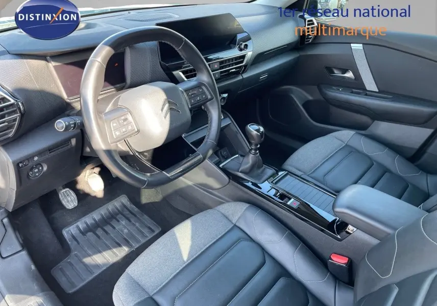Vue intérieure côté conducteur de la Citroën C4 1.2 PureTech 130ch avec volant cuir et sellerie bi-matière gris et noir.