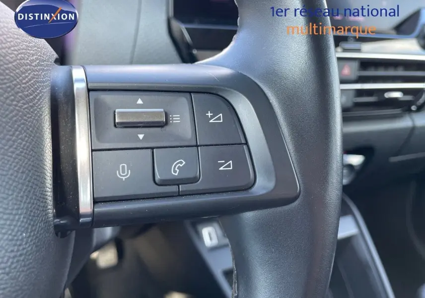 Gros plan sur les commandes au volant à gauche d'une Citroën C4 2021, intérieur noir avec boutons de volume et appel.