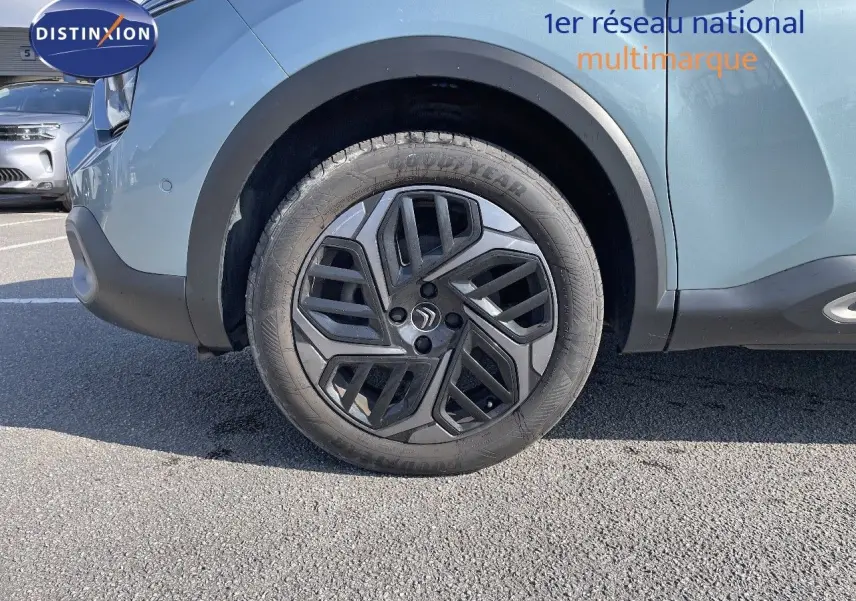 Gros plan sur la roue avant gauche d'une Citroën C4 bleu Iceland Metal avec jante noire au design géométrique.